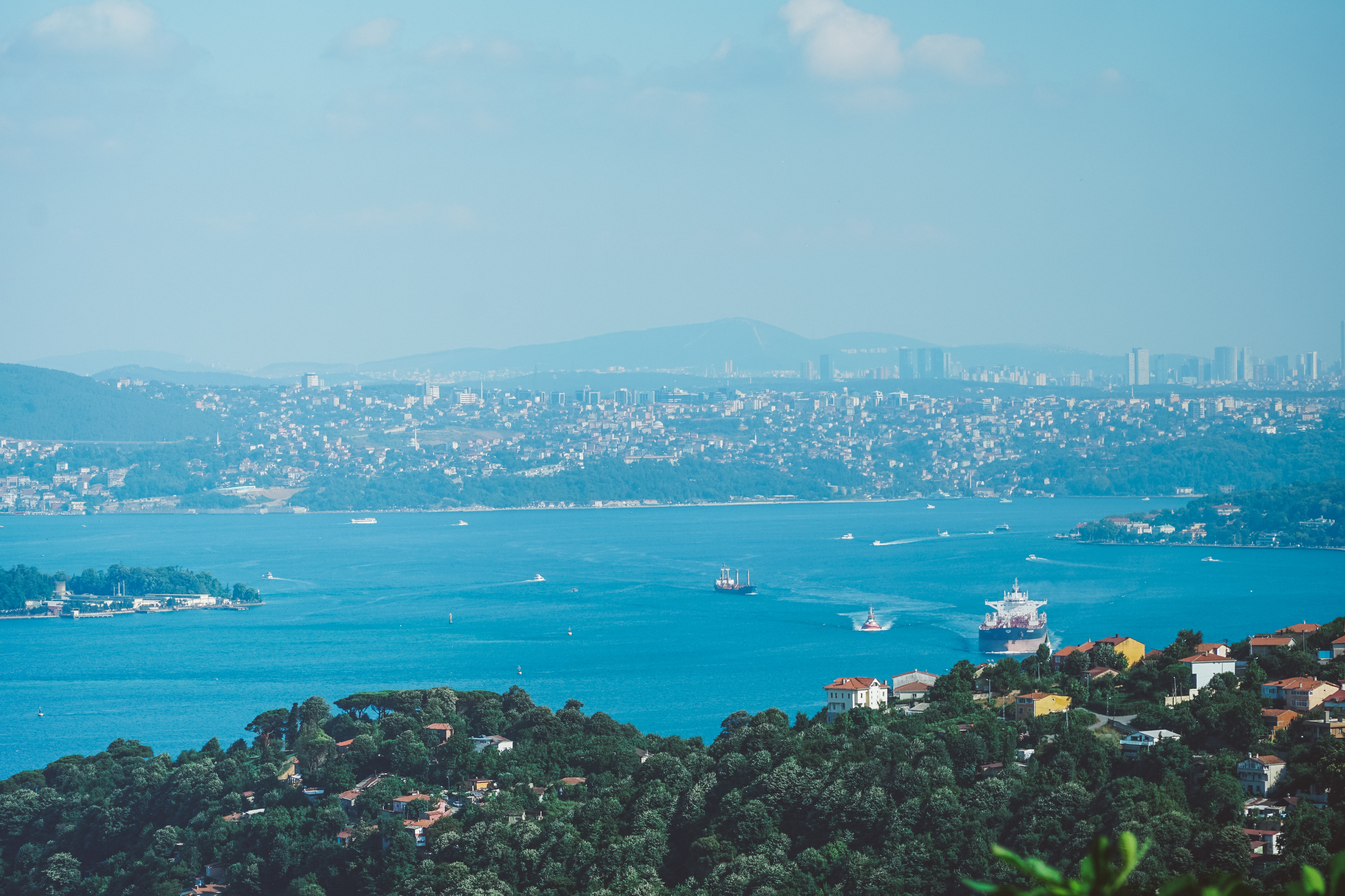 Ships navigate the Bosphorus Strait while trees and building fade into the horizon.