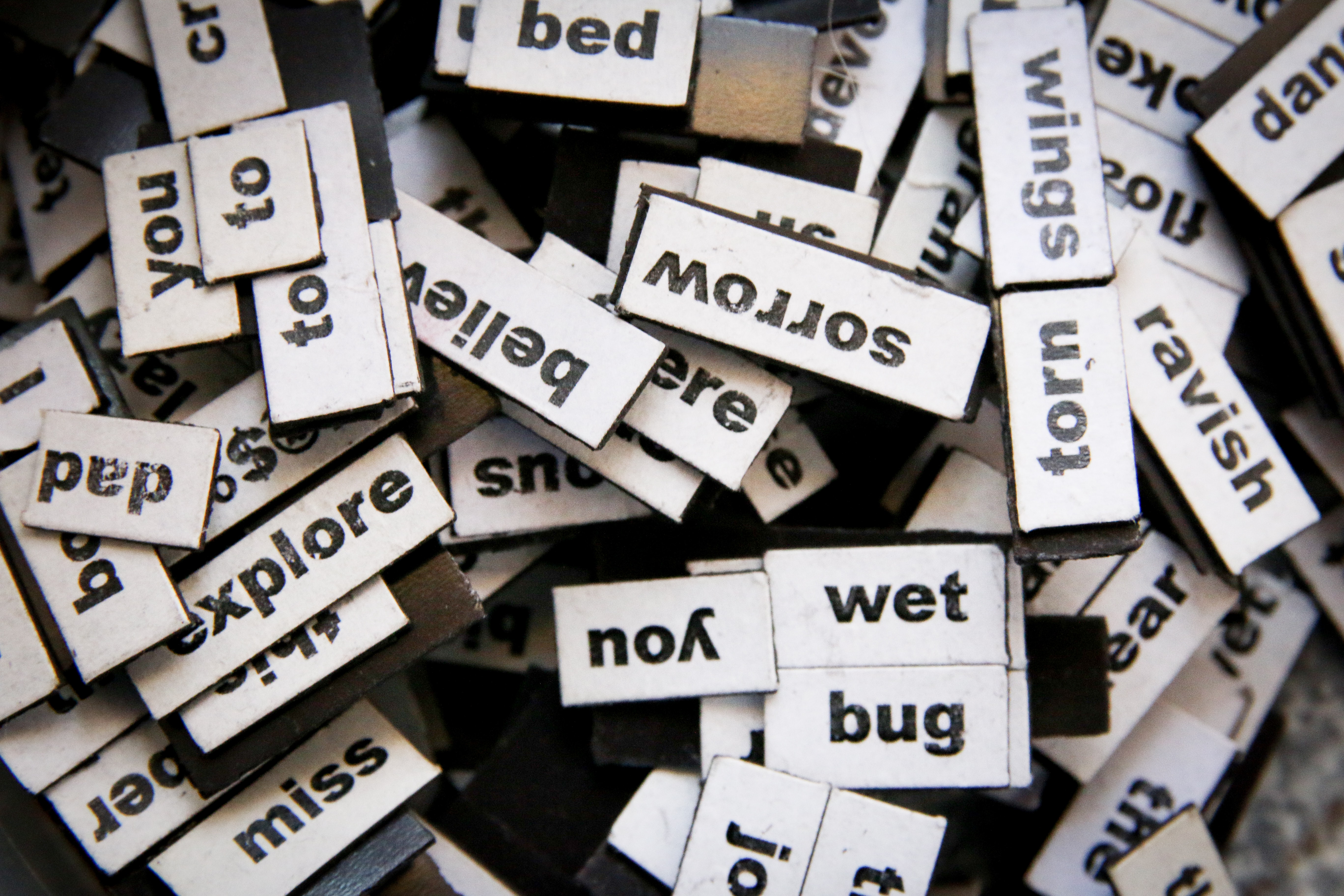 A pile of word magnets sit jumbled up on top of each other.