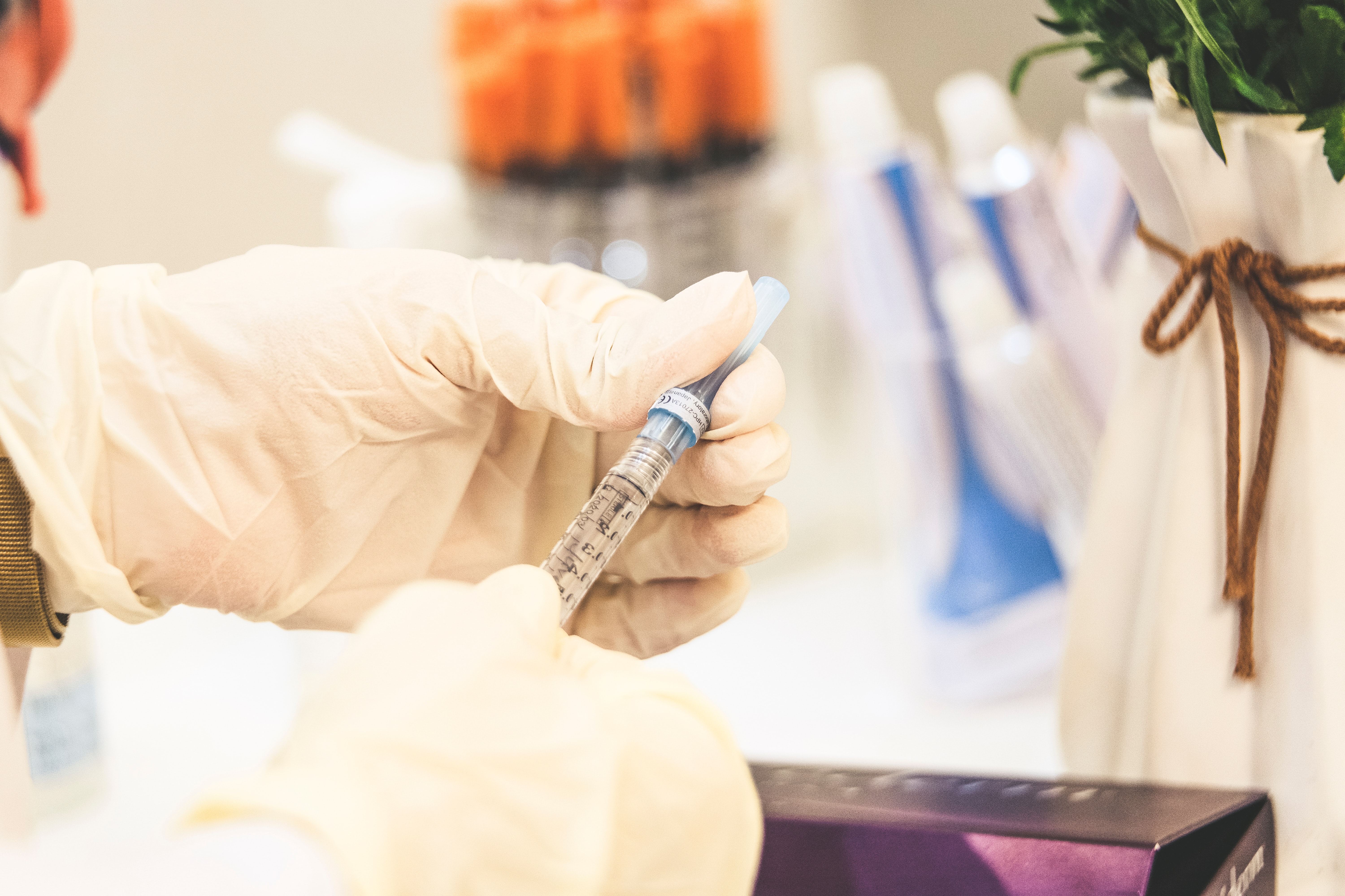 A doctor with white gloves pulls insulin out of a vial with a needle.