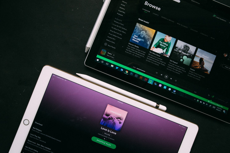 Two tablets display Spotify's desktop app with various playlists.