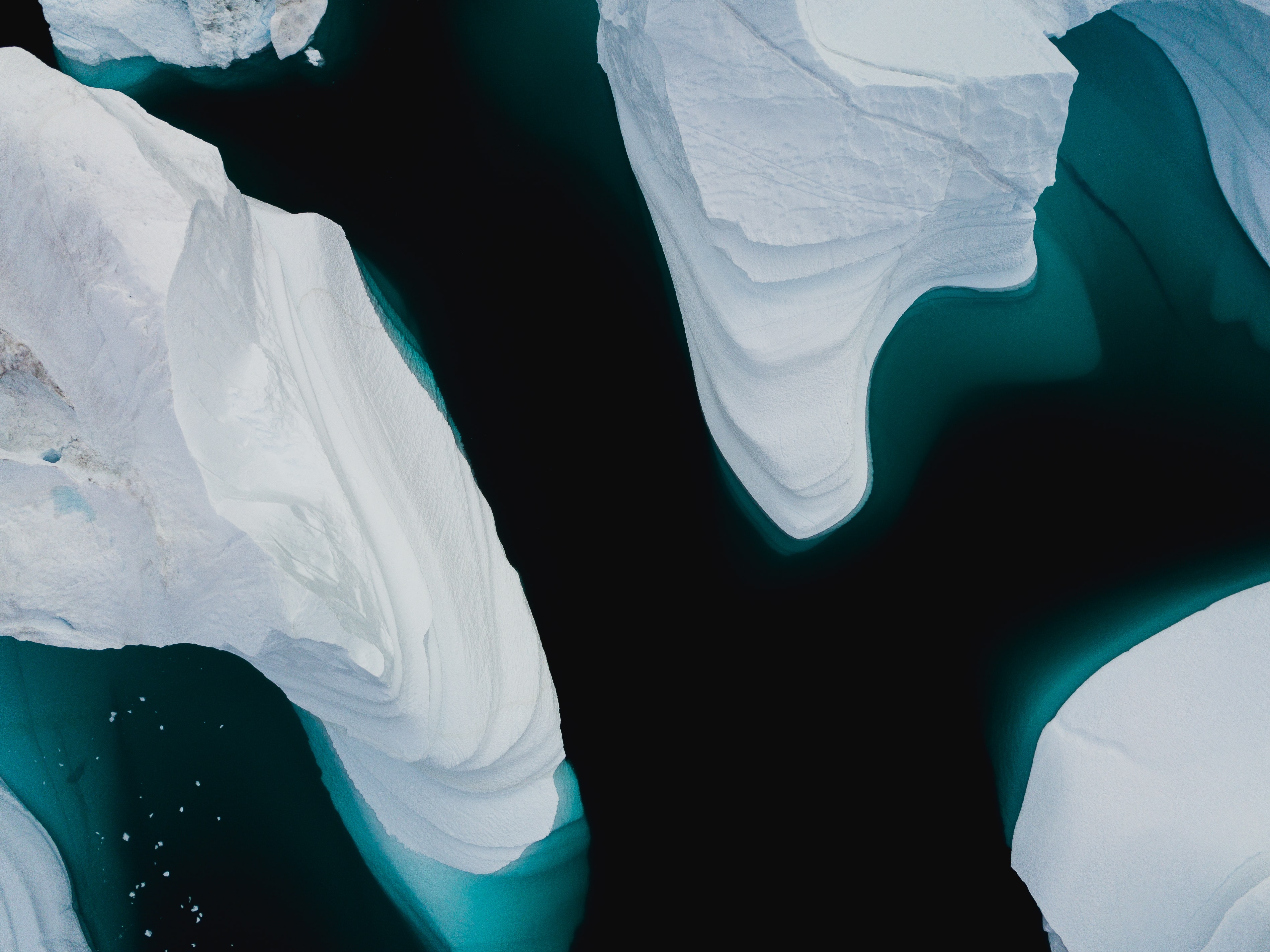 A top-down view of three icebergs half submerged in water.