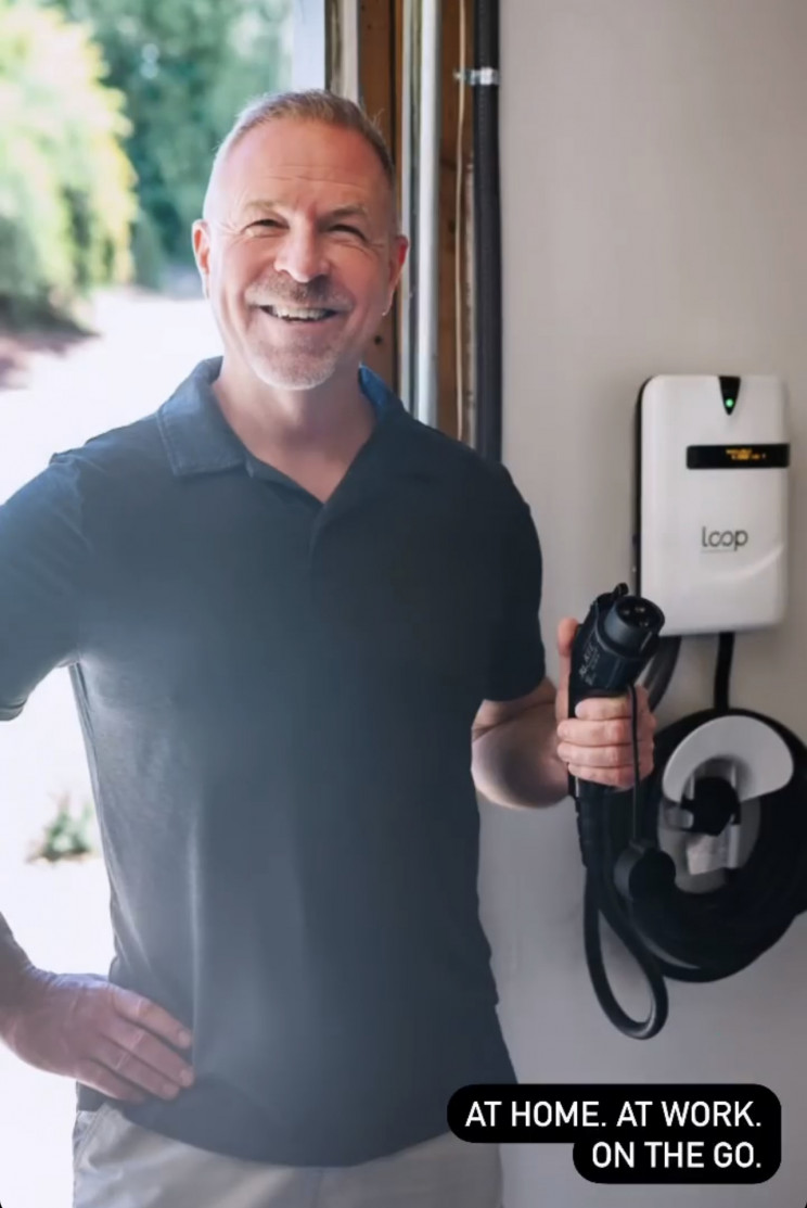 A man holds the charging handle of Loop's EV-Flex charging station.
