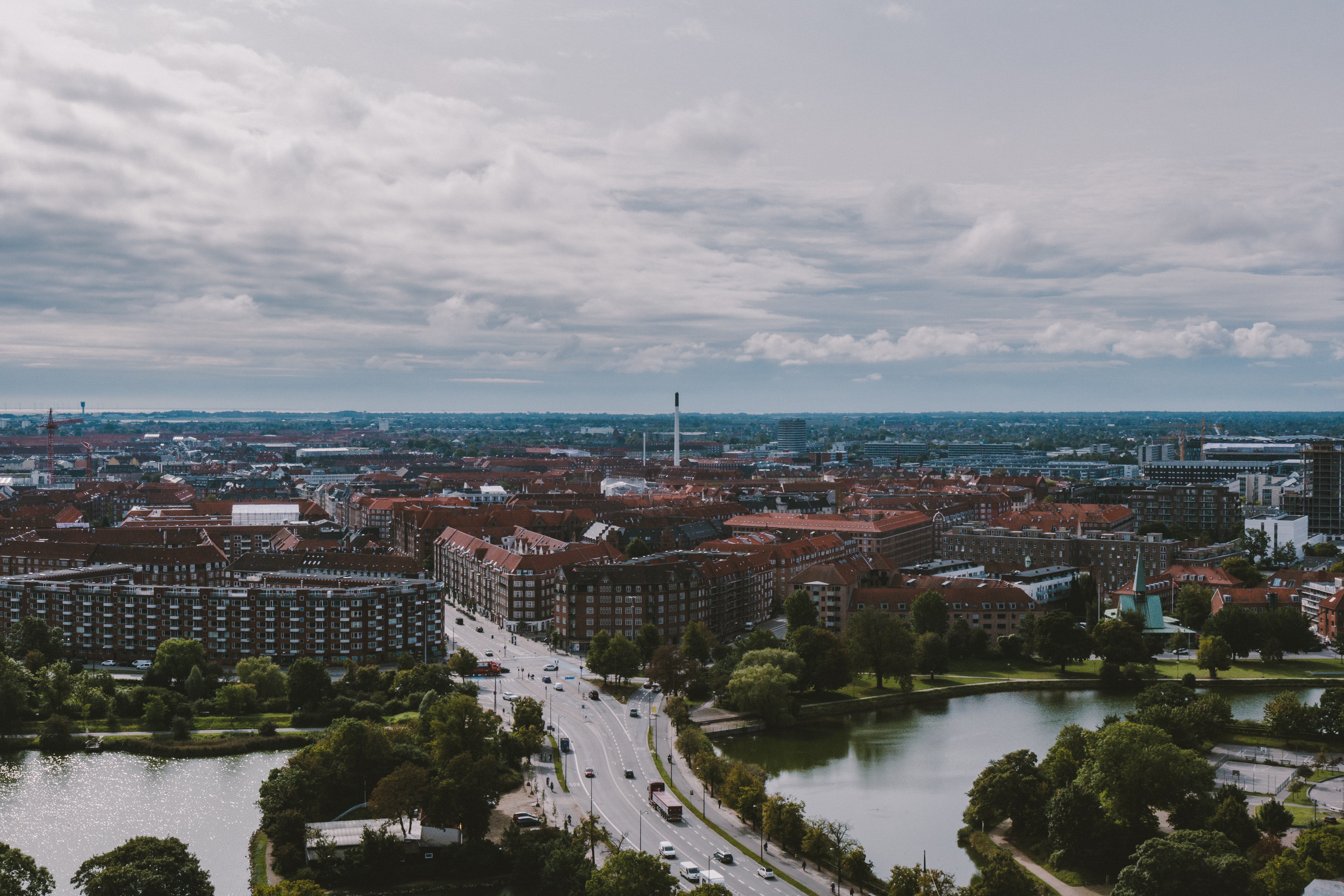 Copenhagen from a nearby hillside, red, tiled-roof buildings and a bridge stretch into the distance under a grey sky.