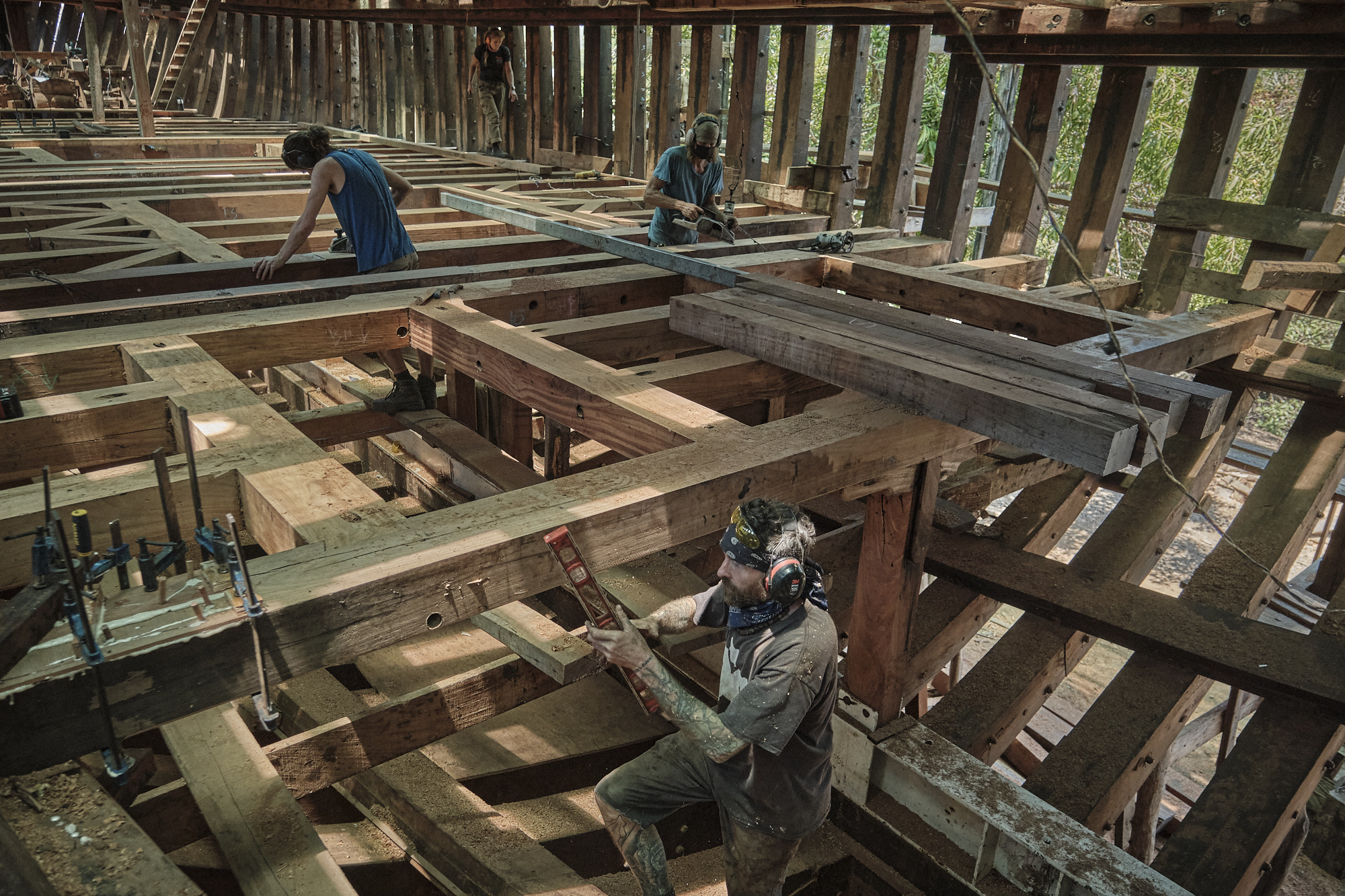 Workers work on a structure of wooden beams as they continue to build the Ceiba ship.