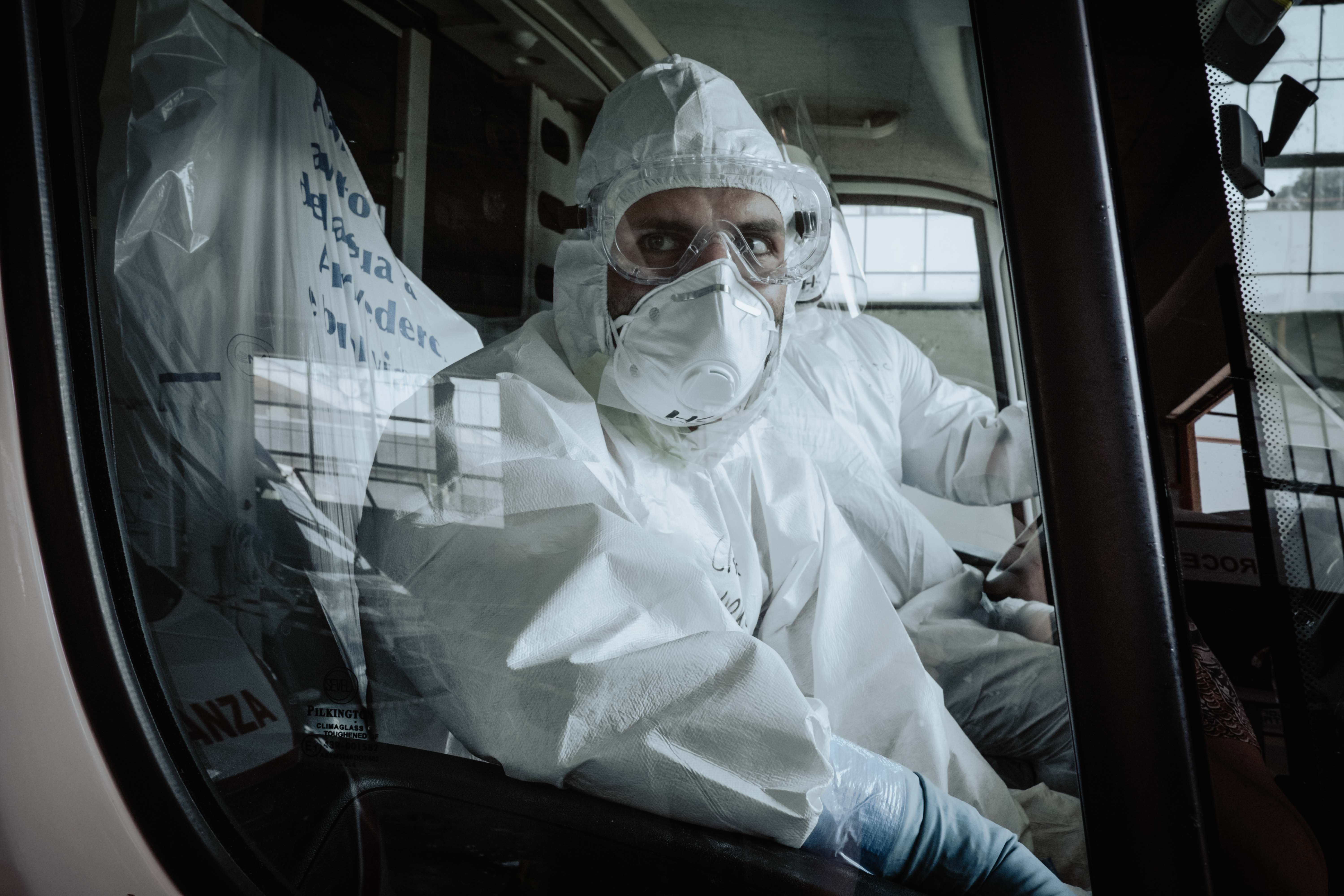 A health worker wearing a full virus protection suit stares out of a car window in Italy.